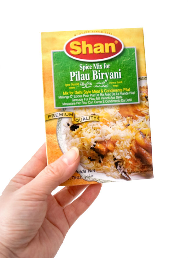 プラウ ビリヤニ マサラ スパイス ミックス - 50g 【Shan】 4 - 手に持ってみました。外箱には、英語、スペイン語等の多国語表記です。箱の中にはウルドゥ語のレシピがあります。こちらの黄色い箱でのお届けになる場合がございます。何卒、ご了承下さい。