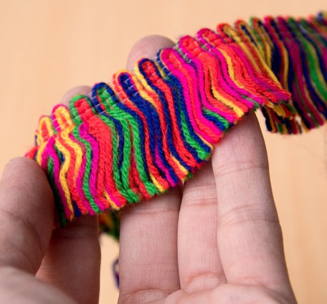 インドのひらひらカラフルテープ - ロール売り【長さ:約15m 幅:約3cm】 2 - サイズ比較のために手に持ってみました。
下部分のナイロン糸を抜くことにより、ひらひらします