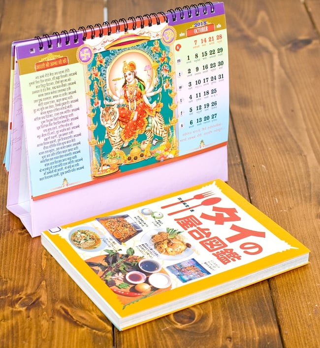 【2018年度版】インドの卓上カレンダー Bhakti Sagar 7 - 縦20cmx横15cmの本と比べてみるとこれくらいの大きさです。（同時サイズの類似商品となります）