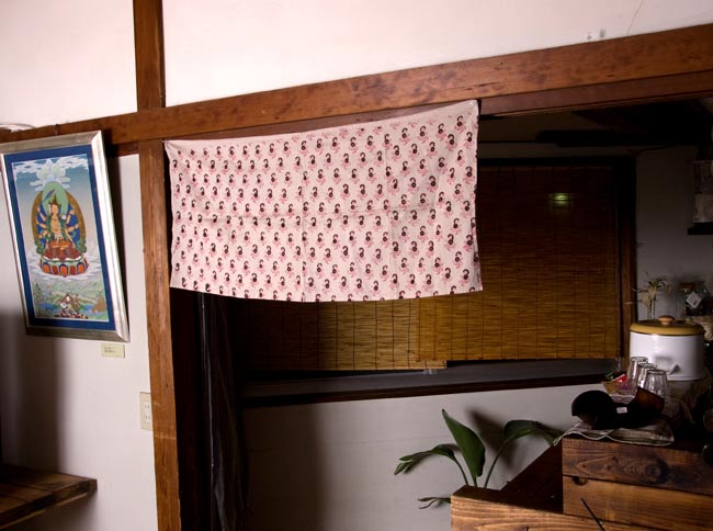 【裏地付き】インドのコットンカフェカーテン【花柄】 - グレー 5 - 柄違い品のカフェでの使用例です。ちょっとした目線隠しから、家具の本棚などに付けたりと使い勝手の良い品です。<br>ちなみに、隣に飾ってある素敵なタンカは、チベット仏画師である飯野博昭さんの作品です!オフィシャルページは<a href="http://www.tokyo-guesthouse.com/thangka/" target="_blank">こちら</a>です。