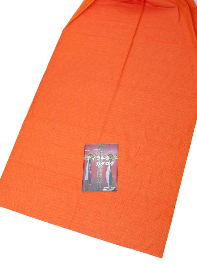 〔1m切り売り〕インドのシンプルコットン布 - 編み模様オレンジ 〔幅約110cm〕の写真1枚目です。A4の冊子と撮影しました布の広がりがわかりますね。切り売り,量り売り布,アジア布 量り売り,手芸,裁縫,生地,アジアン,ファブリック