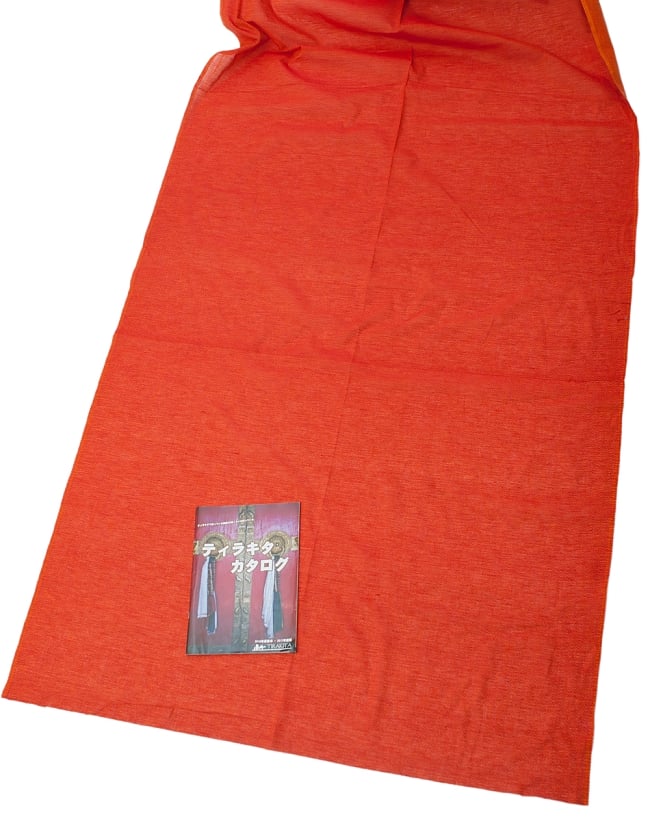 〔1m切り売り〕インドのシンプルコットン布 - 菱形オレンジ 〔幅約110cm〕の写真1枚目です。A4の冊子と撮影しました布の広がりがわかりますね。切り売り,量り売り布,アジア布 量り売り,手芸,裁縫,生地,アジアン,ファブリック