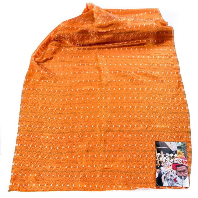 〔1m切り売り〕インドの伝統模様布〔幅約118cm〕 - オレンジ 2 - 布を広げてみたところです。横幅もしっかり大きなサイズ。布の上に置かれているのはサイズ比較用の当店A4サイズカタログです。
