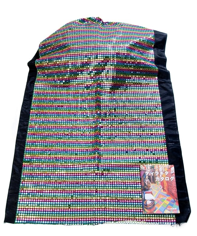 〔1m切り売り〕インドのスパンコールクロス布〔107cm〕 - ブラック×マルチカラー 3 - 布を広げてみたところです。横幅もしっかり大きなサイズ。布の上に置かれているのはサイズ比較用の当店A4サイズカタログです。