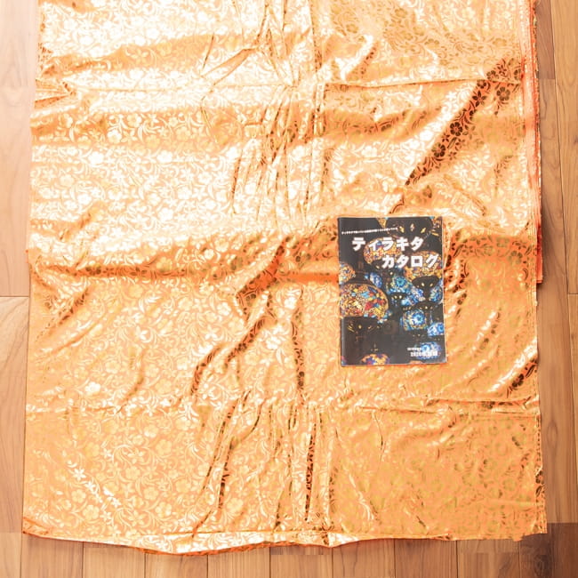 〔1m切り売り〕インドの伝統柄ゴールドプリント光沢布〔幅約100cm〕 7 - 布を広げてみたところです。横幅もしっかり大きなサイズ。右下にあるのはサイズ比較用の当店A4サイズカタログです。