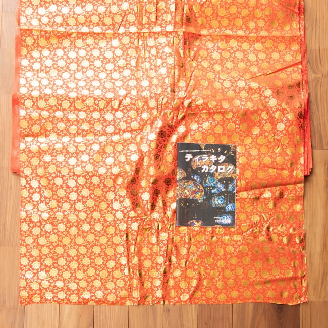 〔1m単位切り売り〕インドの伝統柄ゴールドプリント光沢布〔幅約100cm〕 7 - 布を広げてみたところです。横幅もしっかり大きなサイズ。右下にあるのはサイズ比較用の当店A4サイズカタログです。