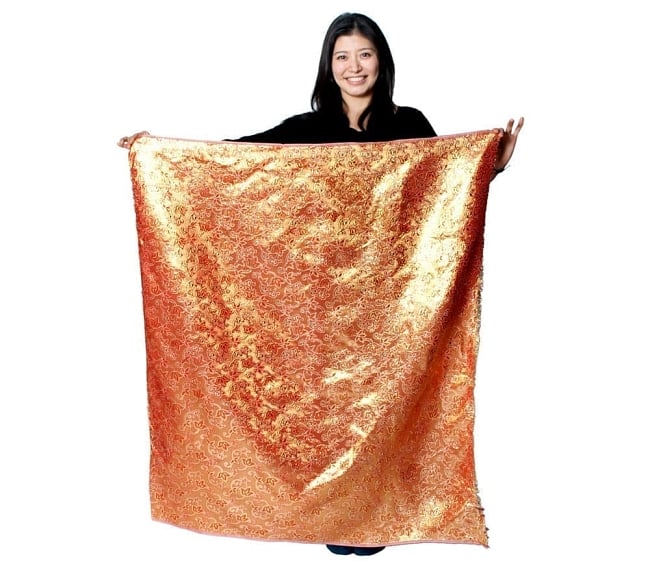 インドの伝統布 ボーダー柄のルンギー用コットン布 〔幅110cm 1メートル切り売り〕レッド×ネイビー 7 - 同じインドからやってきた『〔1m切り売り〕インドの伝統柄ゴールドプリント光沢布〔幅約100cm〕』を、1mカットしてモデルさんに持ってもらった写真です。切り売りの布は基本的に横幅100cm前後と大きいので、ご覧の通り色々な用途に使えそうです。ご注文個数に応じた長さにカットしてお送りいたします。